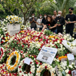 Petugas TPU Tanah Kusir sedang membersihkan gundukan bunga tabur yang melimpah di atas makam penyanyi Vidi Aldiano pada sore hari