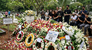 Petugas TPU Tanah Kusir sedang membersihkan gundukan bunga tabur yang melimpah di atas makam penyanyi Vidi Aldiano pada sore hari